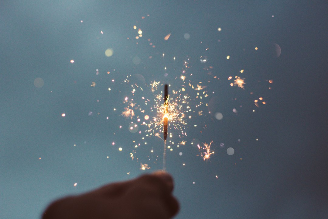 Photo by Cristian Escobar person holding lighted sparklers